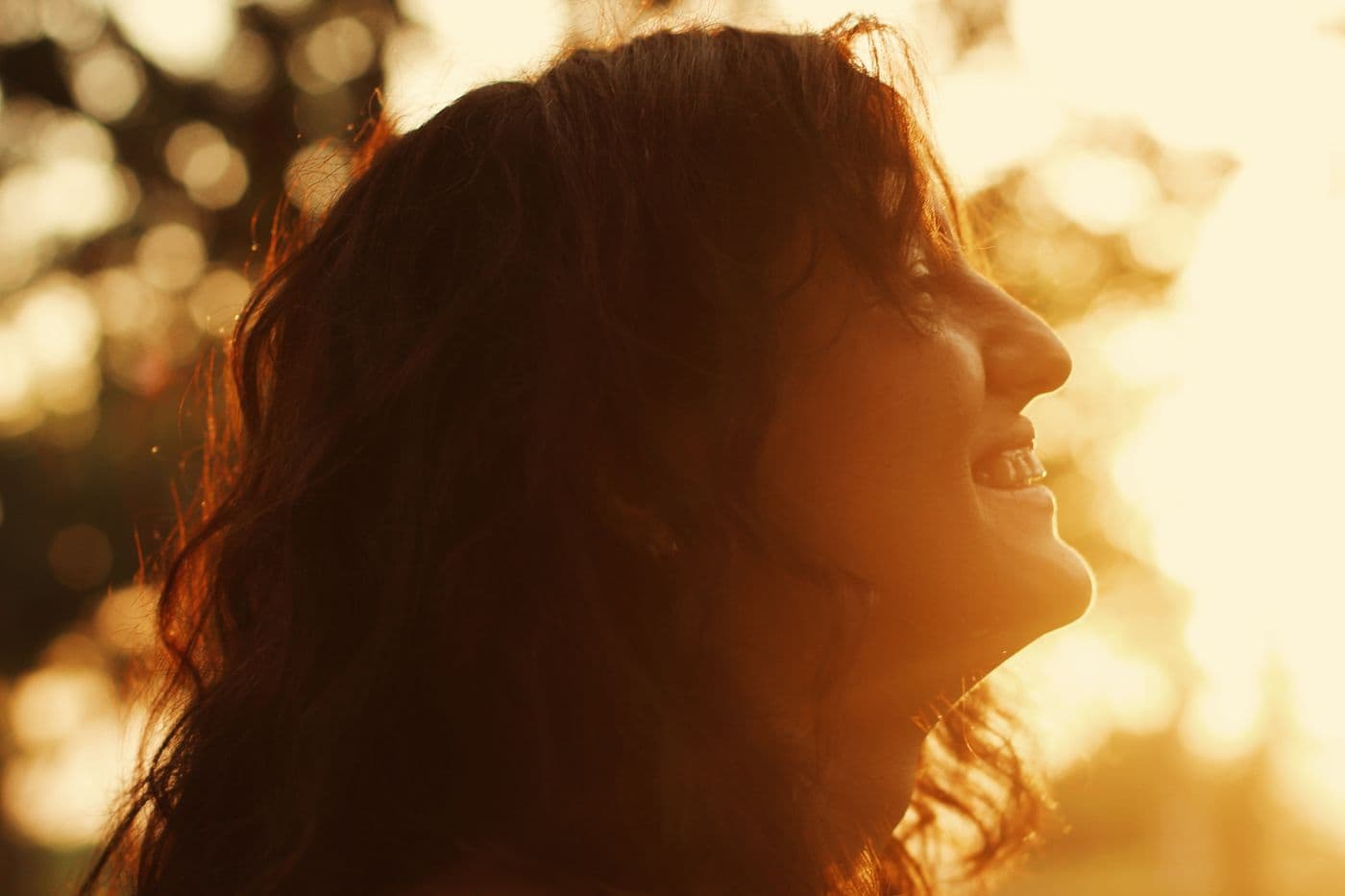 Woman smiling in warm golden sunlight outdoors