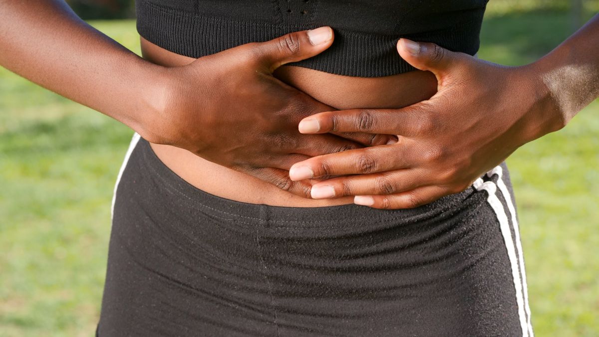 Woman holding her stomach, indicating abdominal discomfort